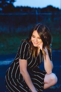 Young woman smiling while sitting by lake