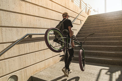 Man moving up with bicycle on staircase