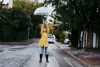 Rear view of woman walking on wet street in city