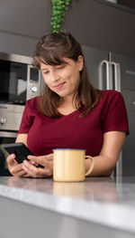 Young woman looking away while sitting on table