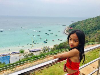 Portrait of young woman standing at beach against sky