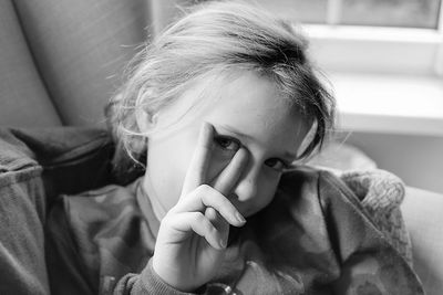Close-up portrait of girl showing peace sign at home