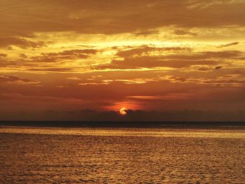 Scenic view of sea against dramatic sky during sunset