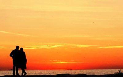 Silhouette people standing on beach against sky during sunset