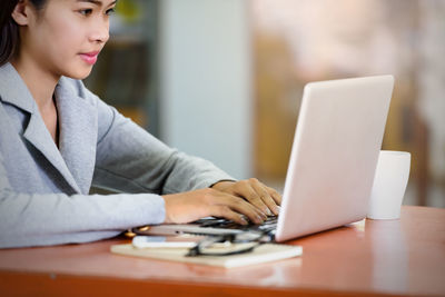 Midsection of woman using mobile phone while sitting on table
