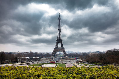 Tower in city against cloudy sky