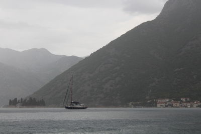 Sailboat sailing on sea against mountains