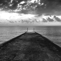 Pier on sea against cloudy sky