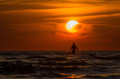 Silhouette man on beach against sky during sunset