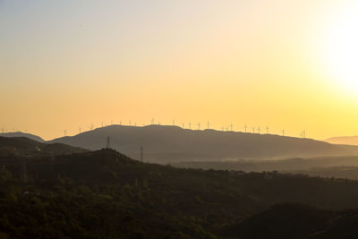 Scenic view of silhouette mountains against orange sky