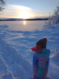 Rear view of girl on snow during sunset