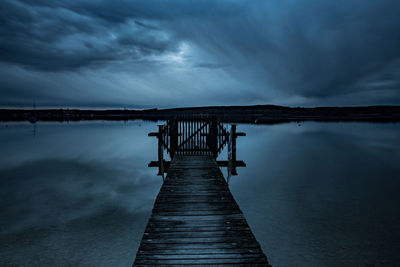 Pier over lake against sky at dusk