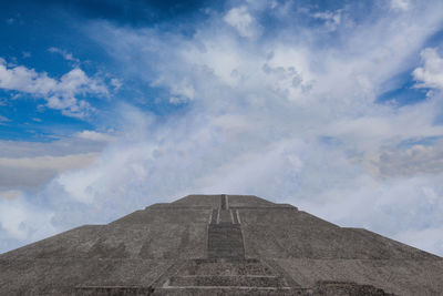 Low angle view of pyramid against cloudy sky