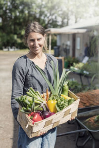 Portrait of happy woman carrying vegetables in basket