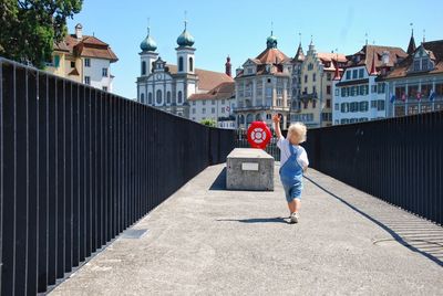 Full length of boy on building in city against sky