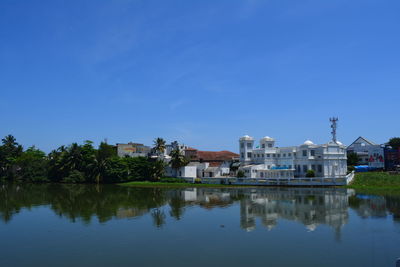 Reflection of buildings in water against clear blue sky