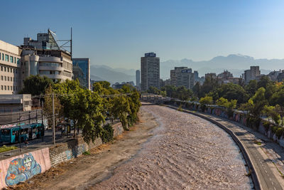 Street amidst buildings in city against clear blue sky