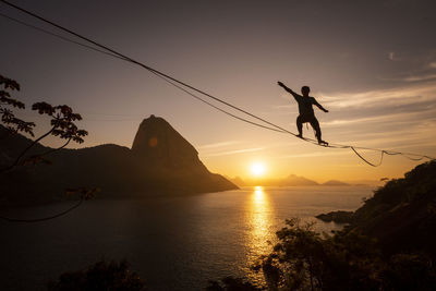 Beautiful sunrise view of man walking on highline with sugar loaf