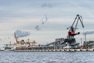 Cranes at commercial dock against sky