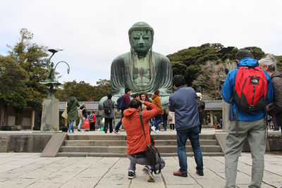 Rear view of people on sculpture against sky