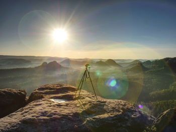 Digital photo camera with tripod record video during sunrise in the fog, outdoors artist equipment