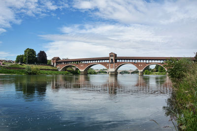 Arch bridge over river against sky