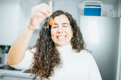 Portrait of smiling woman holding food in kitchen