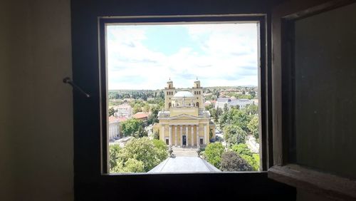 Buildings against sky seen through window