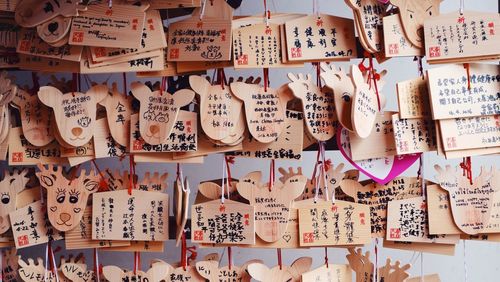 Close-up of wishing labels hanging against wall at temple