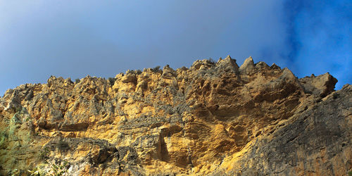 Low angle view of rocky mountains against sky