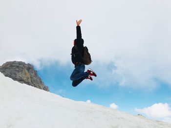 Low angle view of man jumping against sky