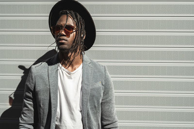 Young man wearing sunglasses standing against wall