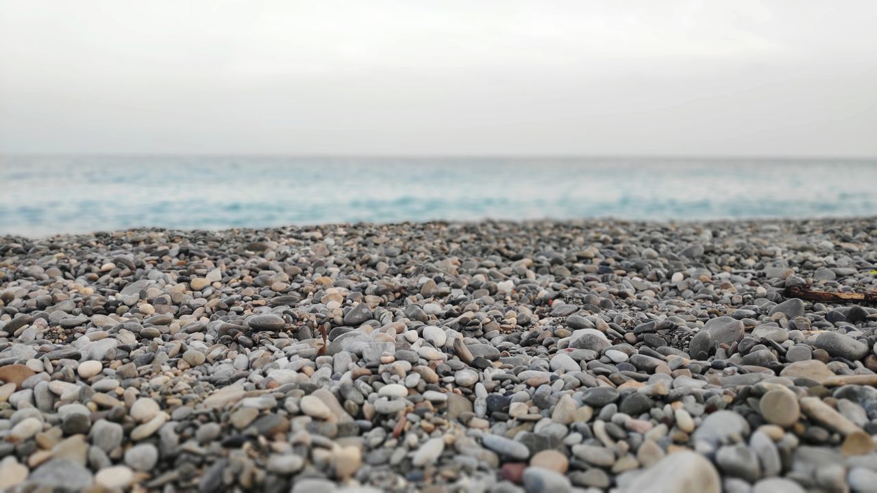 sea, beach, water, land, rock, solid, horizon over water, horizon, sky, scenics - nature, stone - object, pebble, stone, beauty in nature, nature, rock - object, no people, day, tranquility, outdoors, surface level, gravel