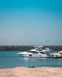 Boats in sea against clear blue sky