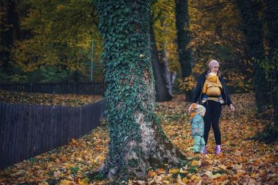 Mother with children playing in autumn with colored leaves