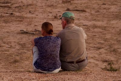 Rear view of senior couple sitting on field