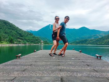 Full length of couple standing by lake on pier