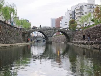 Bridge over river in city against sky