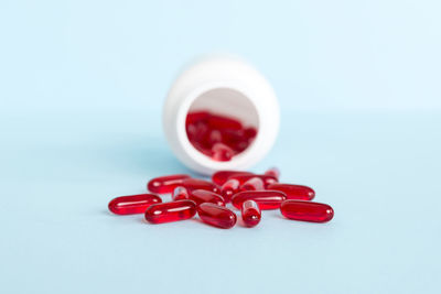 Close-up of pills spilling from bottle against white background