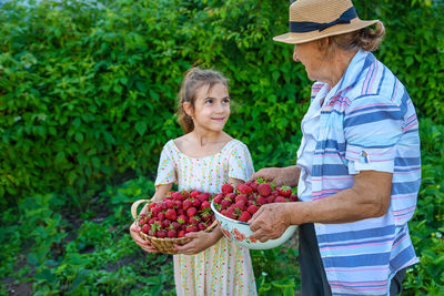 Smiling girl with grandmother holding bowl of strawberries