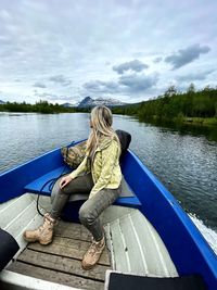 Woman sitting on boat in lake against sky