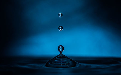 Close-up of drop falling in blue water