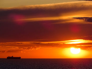 Scenic view of sea against dramatic sky during sunset