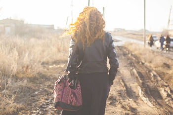 Rear view of woman walking on field