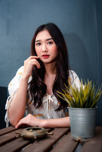 Portrait of beautiful young woman sitting on table