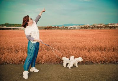 Woman pointing while standing with dogs on road