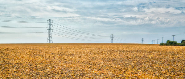 Electricity pylon on field against sky