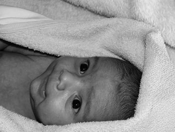 Close-up of cute baby boy lying on towel