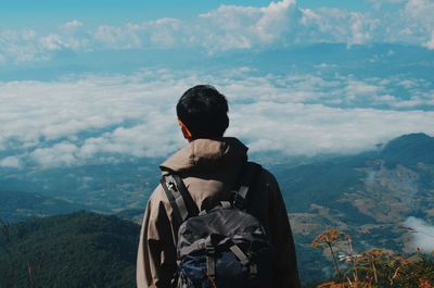 Rear view of man looking at mountains against sky