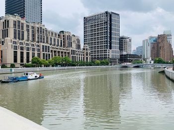 River by modern buildings in city against sky